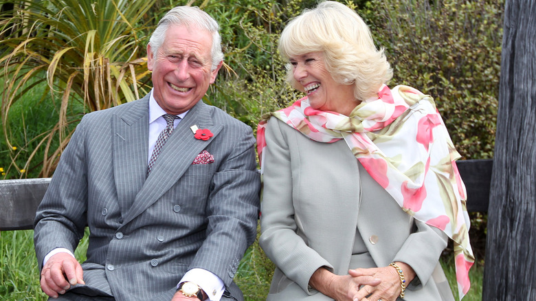 King Charles and Queen Camilla sitting outdoors laughing