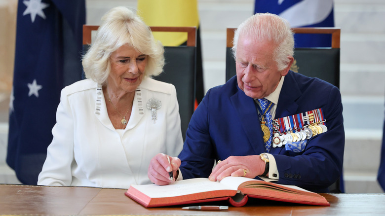 Queen Camilla (left) and King Charles (right) signing a book in 2024