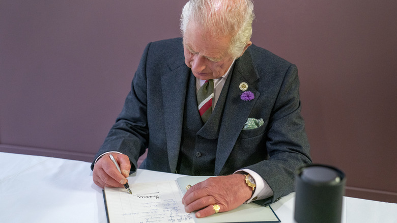 King Charles signing a book