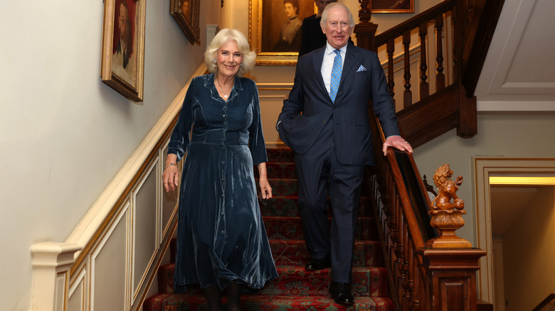 Queen Camilla and King Charles standing on the grand staircase of Clarence House in their finery