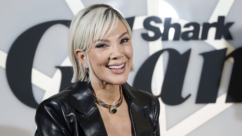 A blonde Kris Jenner smiling while posing at an event