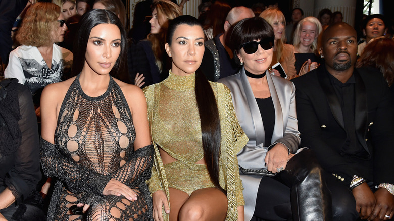 Kim Kardashian, Kourtney Kardashian, Kris Jenner, and Corey Gamble seated at a Balmain runway show.