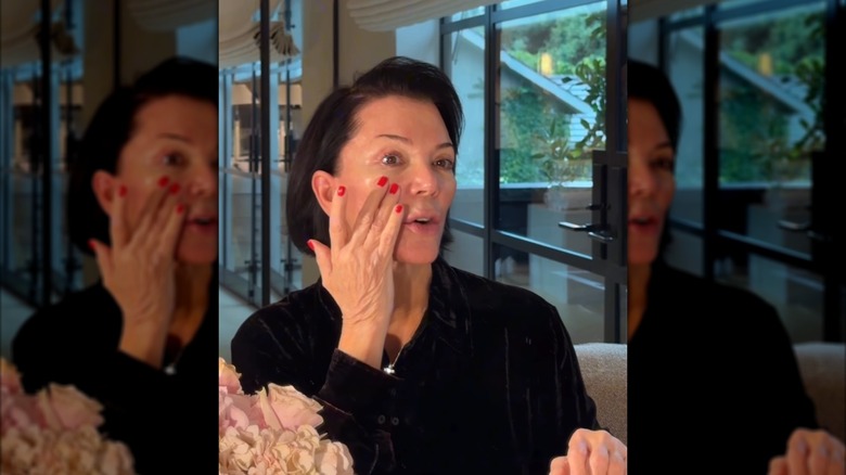 Kris Jenner touching her face.