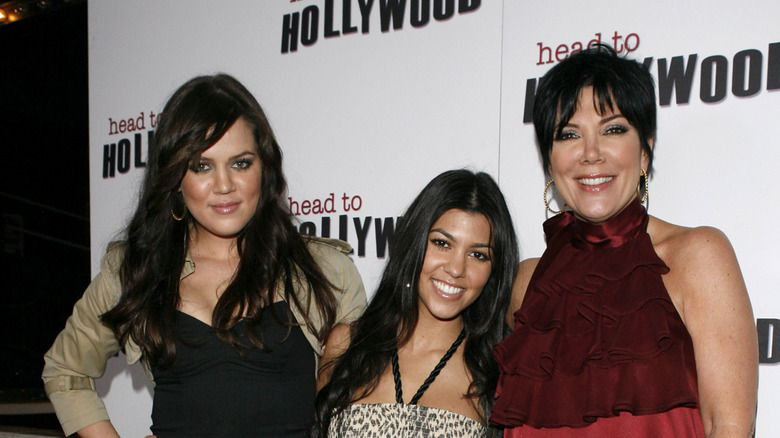 Khloé and Kourtney Kardashian with Kris Jenner smiling on step-and-repeat