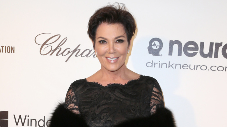 Kris Jenner in black at an event with a large fur wrap
