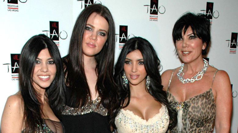 Kourtney, Khloé, and Kim Kardashian posing with Kris Jenner on step-and-repeat