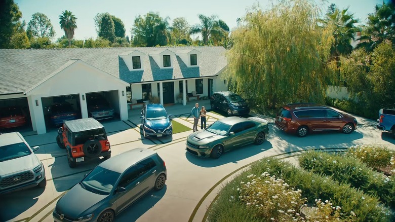 An aerial shot of Kristen Bell and Dax Shepard in their driveway surrounded by several cars.