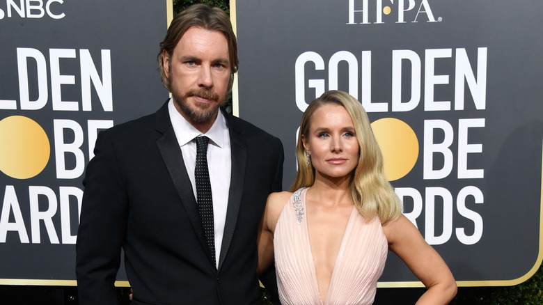Dax Shepard with a serious expression and Kristen Bell slightly smiling with her arm around him at the 2019 Golden Globes.