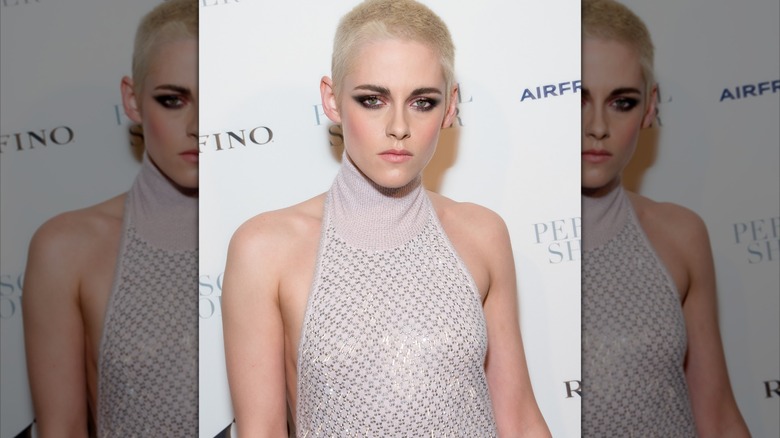A close-up of Kristen Stewart with a bleached blond buzz cut and sparkly dress.