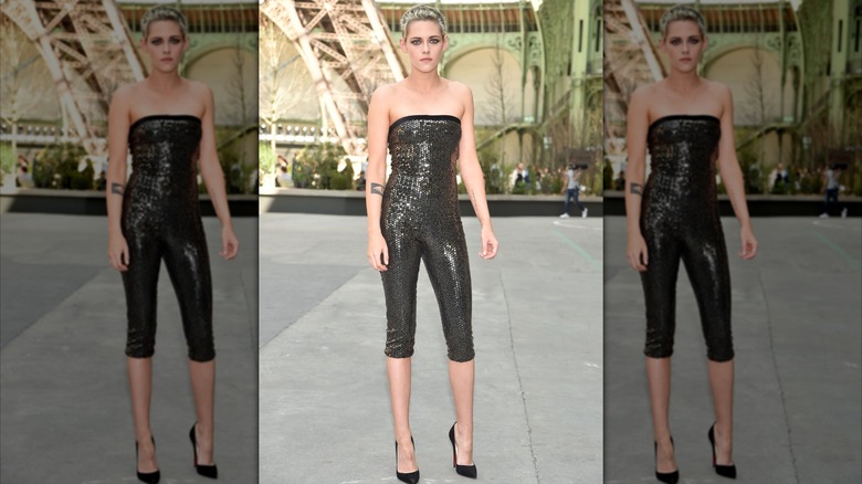 Kristen Stewart wearing a black sequined jumpsuit at a fashion show.