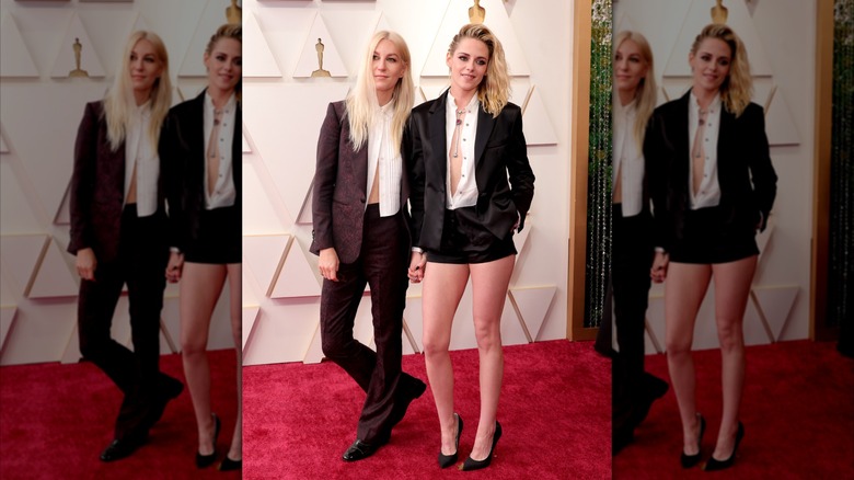 Kristen Stewart and Dylan Meyer wearing matching black suits on a red carpet