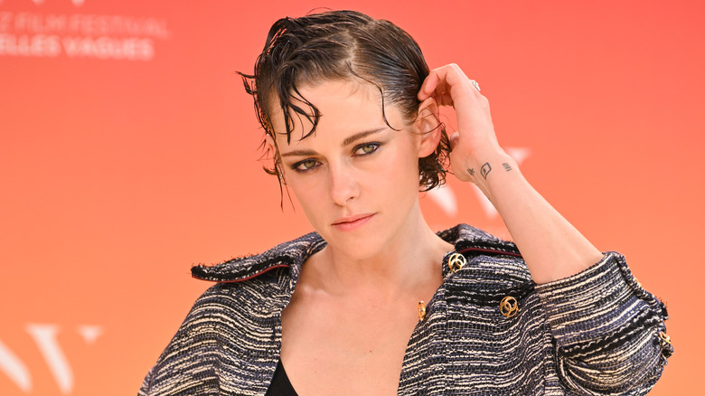 A close-up of Kristen Stewart wearing Chanel against an orange backdrop.