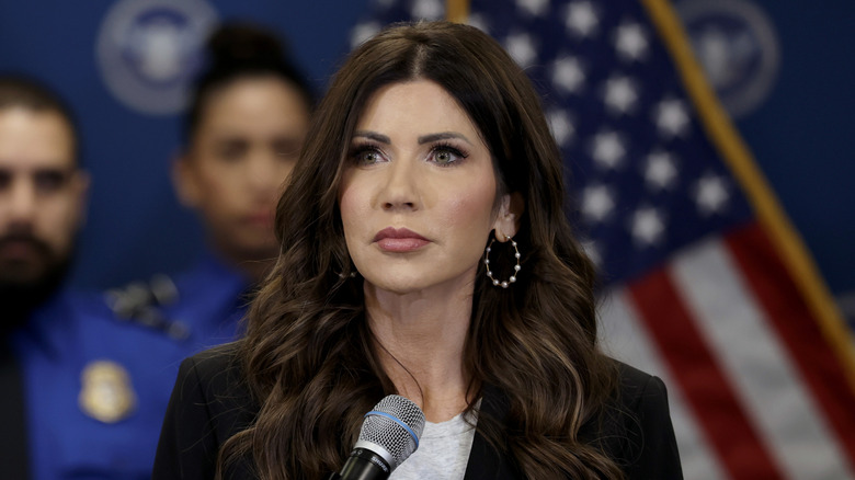 Kristi Noem in front of microphone looking serious