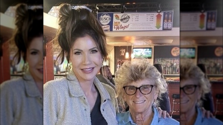Kristi Noem with her hair in a messy updo smiling alongside Jean Hunhoff
