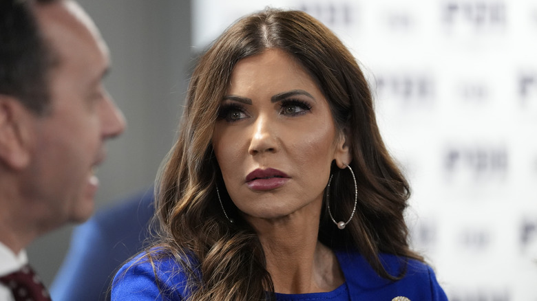 Kristi Noem looking at someone talking while wearing blue and big hoop earrings