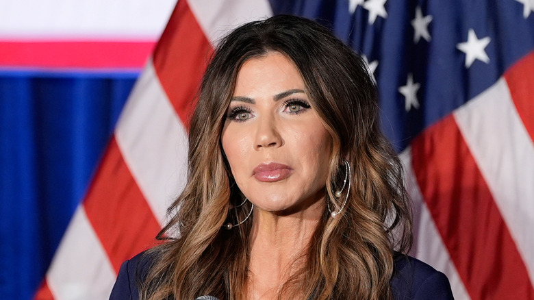 Kristi Noem posing in front of the flag
