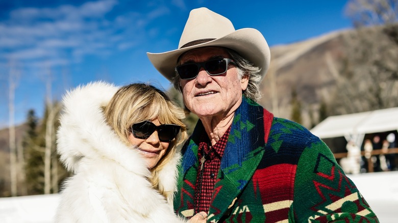 Goldie Hawn, wearing a white fur coat, poses for a picture with Kurt Russell in a colourful jacket and a cowboy hat.