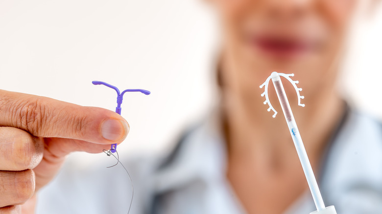 Doctor holding two kinds of IUDs.