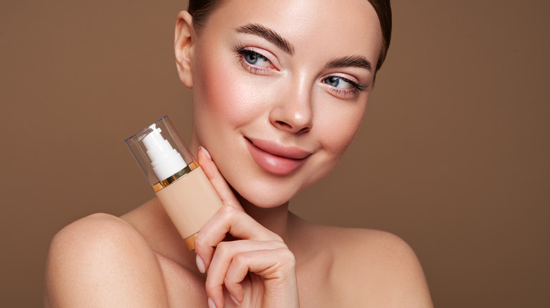 woman smiling holding foundation