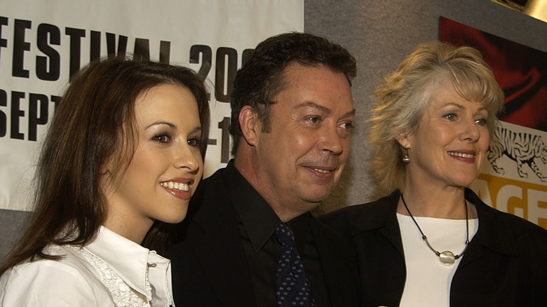 Tim Curry, Lacey Chabert, and Lynn Redgrave smiling while posing together at an event