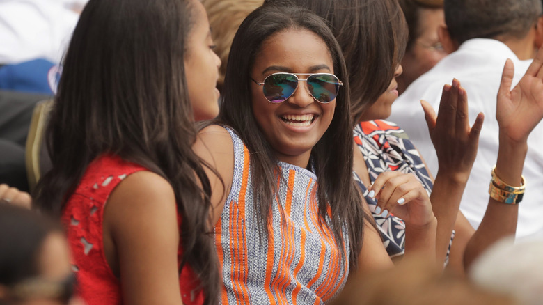 Sasha Obama laughing in sunglasses and a stripy shirt