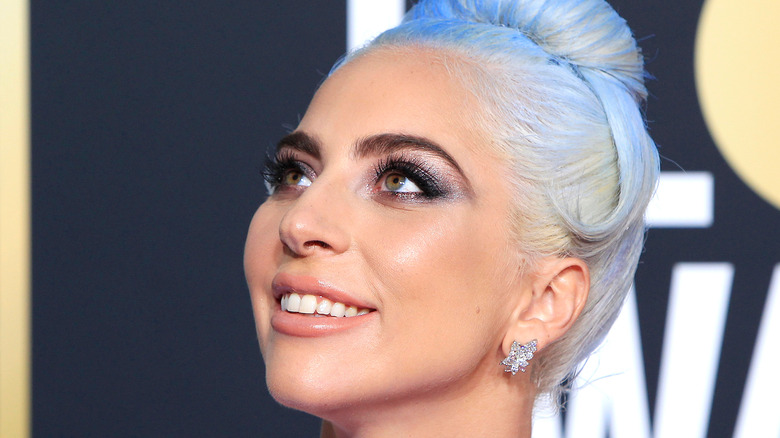 Lady Gaga smiling at award show with blue hair 