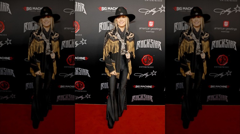 Lainey Wilson on the red carpet in a cowboy inspired outfit.
