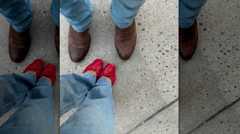 Michelle Randolph's red shoes standing by Glen Powell's cowboy boots