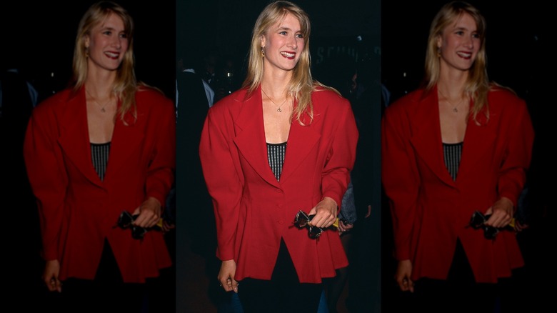 Laura Dern smiling in a puffy red vbazer with matching lipstick and a textured black and white shirt