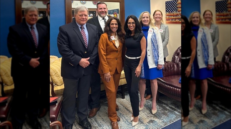Lauren Boebert in a tight top and black trousers posing for a photo with hunting rights club employees