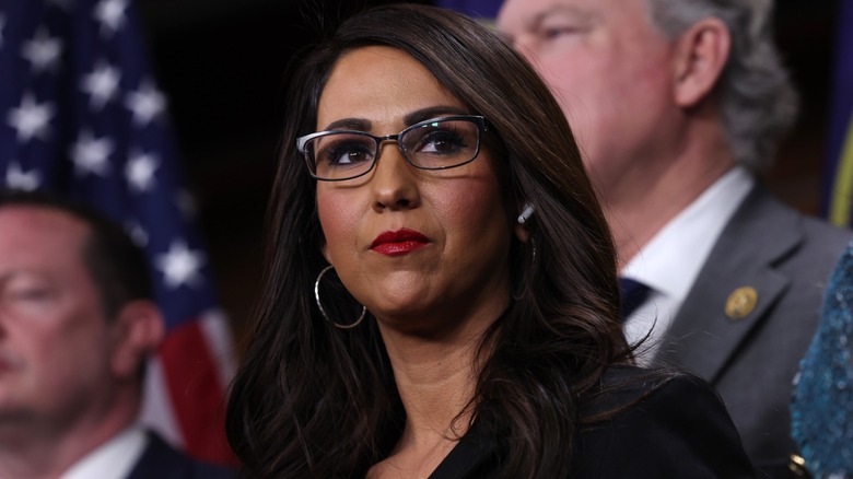 Lauren Boebert staring off into space while wearing red lipstick and her signature glasses