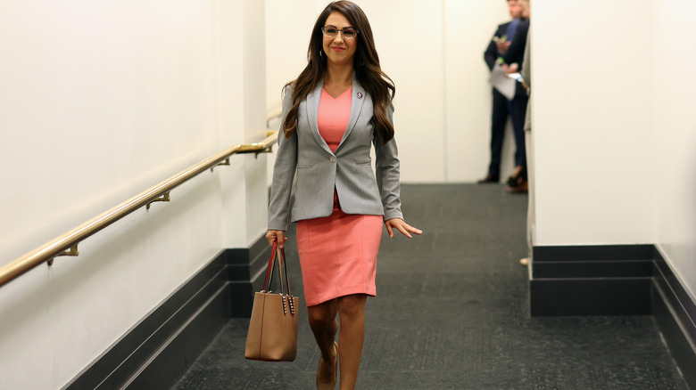 Lauren Boebert prancing down a hallway in a salmon-colored dress