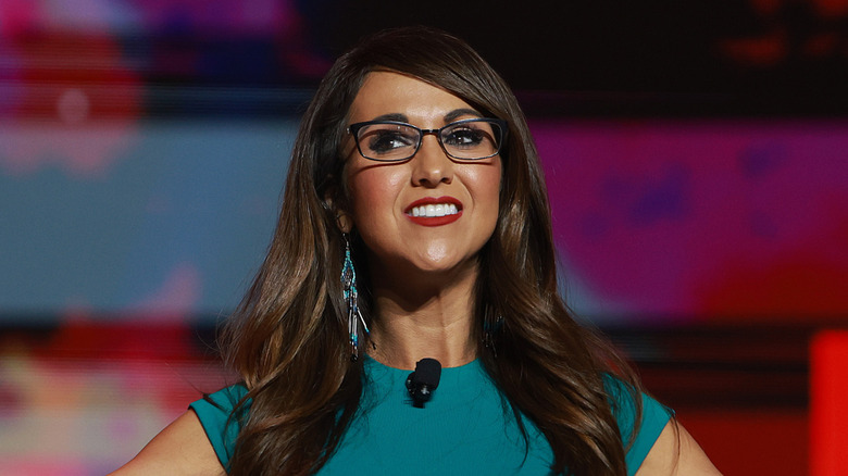 Lauren Boebert smiling on stage in a green dress while at the Turning Point Student Action summit.