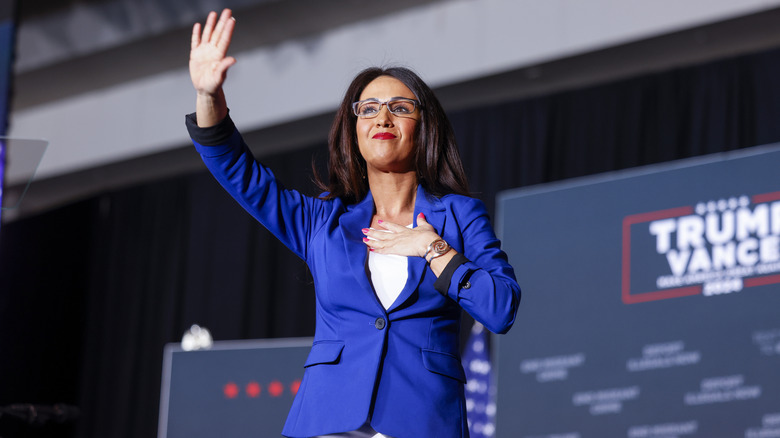 Lauren Boebert stands onstage with arm outstretched