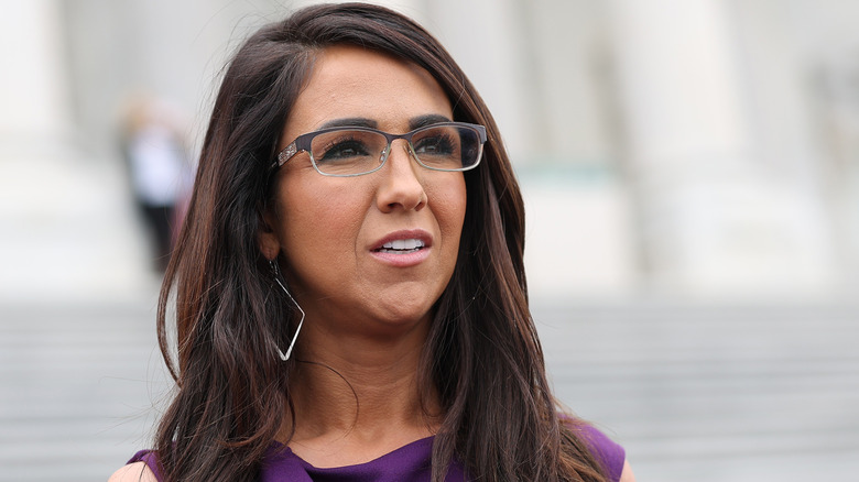 Lauren Boebert in front of steps wearing glasses and purple dress