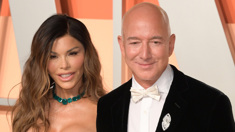 Lauren Sanchez smiling in a white dress next to Jeff Bezos who's wearing a suit.