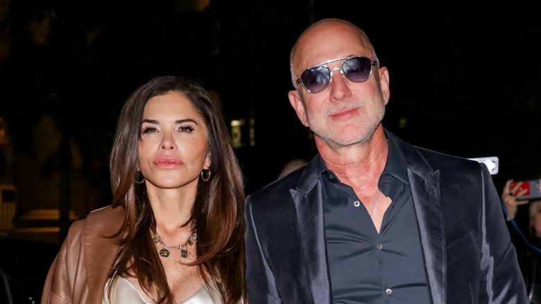 Lauren Sánchez Bezos and Jeff Bezos walking together at night, both pouting