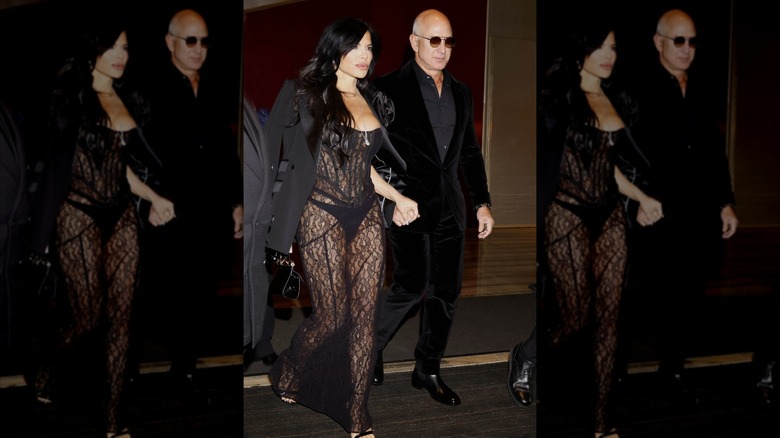 Lauren Sanchez wearing a see-through black dress and coat while holding hands with Jeff Bezos.