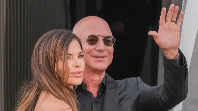 Jeff Bezos waving next to Lauren Sánchez Bezos