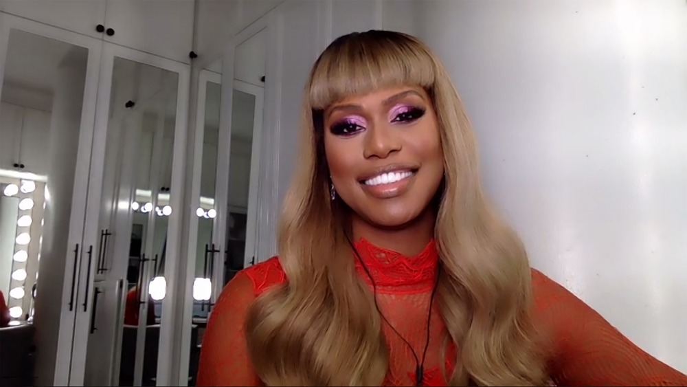 Laverne Cox smiling, blond hair, purple eyeshadow