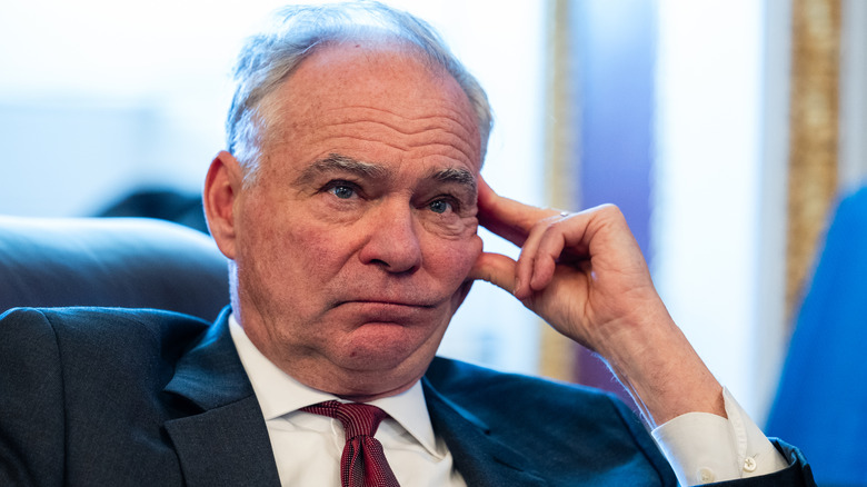 Tim Kaine looking disheartened in a dark suit with a red tie