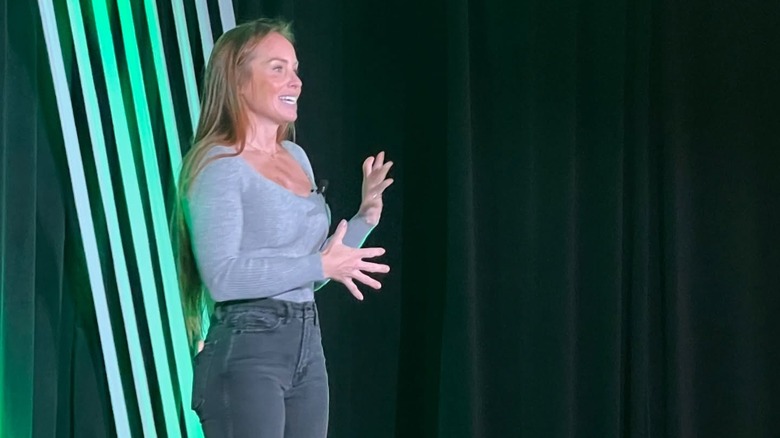 Mina Hawk stands onstage speaking at an event