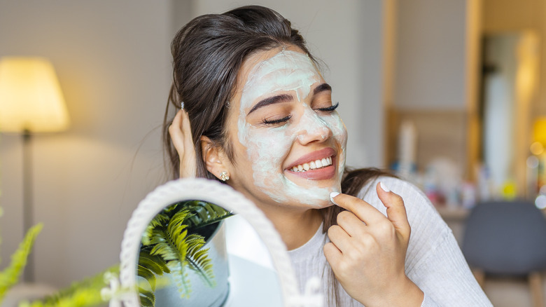 Woman smiling while doing a face mask