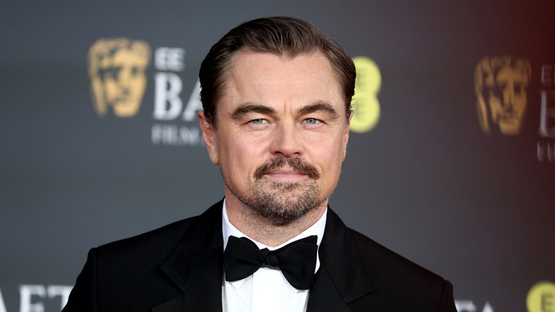 Leonardo DiCaprio posing wearing a black tux with bow tie.