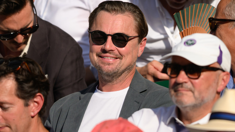 Leonardo DiCaprio smiling in a white shirt and sunglasses