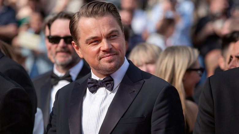 Leonardo DiCaprio looking to the side and smiling in a tuxedo