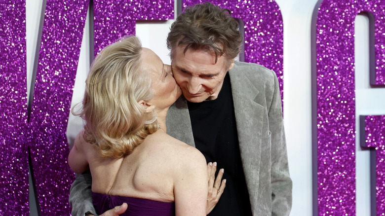 Pamela Anderson kissing Liam Neeson's cheek in a strapless dress