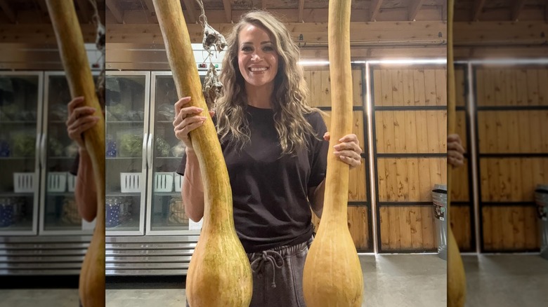 Carrie Underwood smiling and holding two large squash