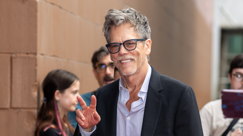 Kevin Bacon holding up a peace sign