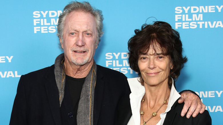 Bryan Brown looking into the distance with his arm around a smiling Rachel Ward